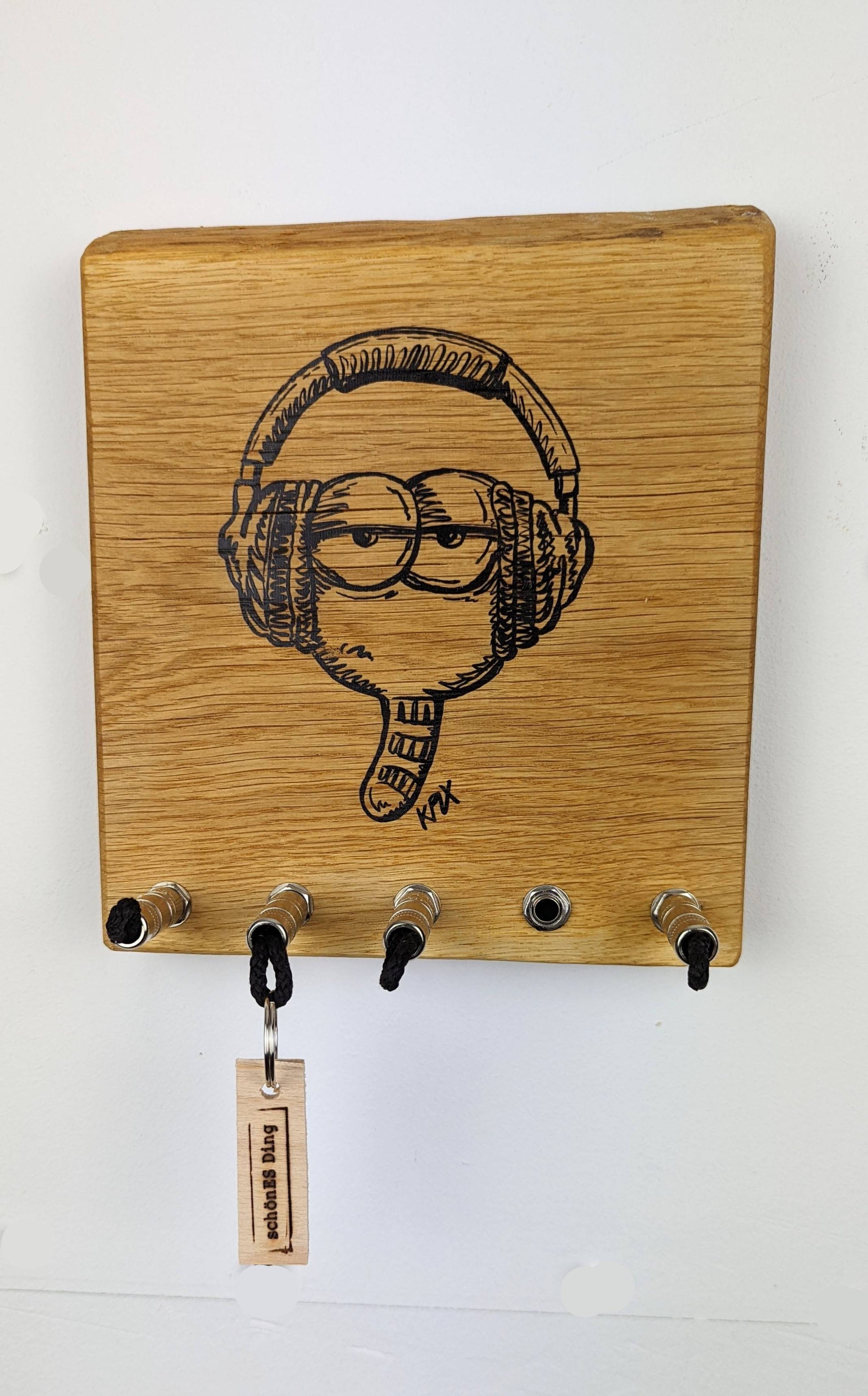 Schlüsselboard aus Holz mit Klinkenstecker.
Mit einem Motiv von KPLX  (https://www.kplx.art/)
Der Klinkenstecker kommt einfach an den Ring des Schlüssels. Mit einem „click“ steckt er im Board und kann so beim Gehen auch wieder herausgezogen werden.
So einfach kann Ordnung sein!
Und weil es Spaß macht, macht ihr es auch (ja, auch die Person, von der ihr gerade denkt: „Never, der nicht!“).
Nie wieder den Schlüssel suchen.
www.schönesding.de
